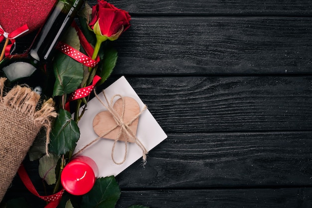 Una botella de vino tinto y un ramo de rosas rojas. Día de San Valentín. Sobre un fondo de madera. Vista superior. Espacio libre para su texto.