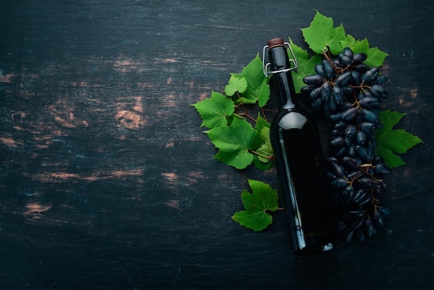 Una botella de vino tinto sobre un fondo de madera negra Uva Espacio libre para texto Vista superior