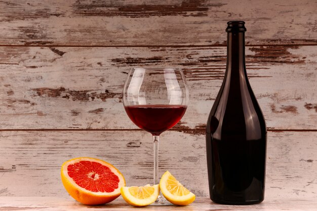 Botella de vino tinto sobre madera, manzana y granada