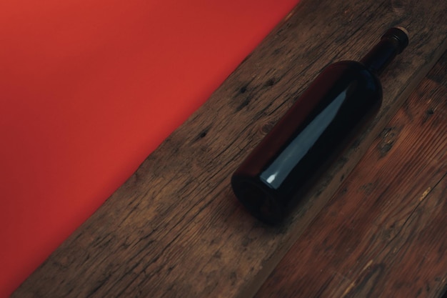 Botella de vino tinto en una vieja mesa de madera de roble y fondo naranja de coral