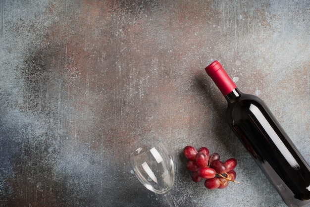 Botella de vino, uva y vasos sobre fondo oscuro de piedra, espacio de copia, vista superior