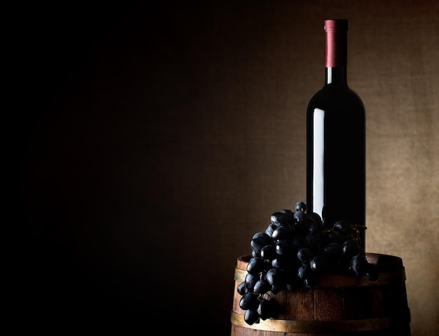 Foto botella de vino con uva en un viejo barril de madera