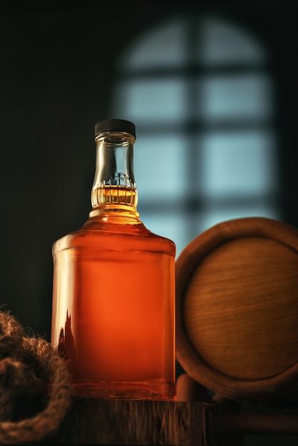 Foto botella de whisky con barril en la bodega.