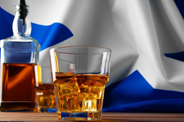 Botella de whisky contra la bandera de Escocia.