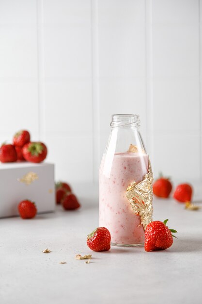 Botella de yogur de fresa o leche en el cuadro gris y bayas en el fondo