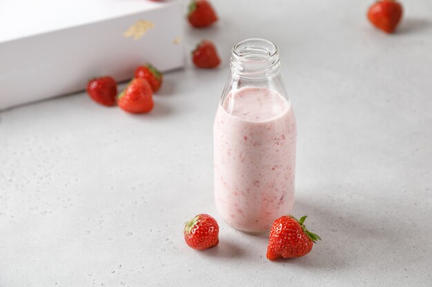 Botella de yogur de fresa o leche en el cuadro gris y bayas en el fondo