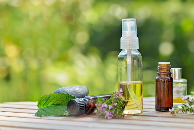 Botellas de aceite esencial en una mesa de jardín con plantas aromáticas