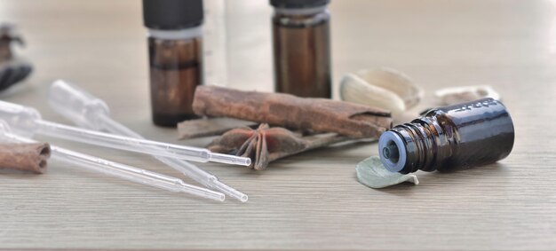 Botellas de aceite esencial y rama de canela y anís en una mesa de madera