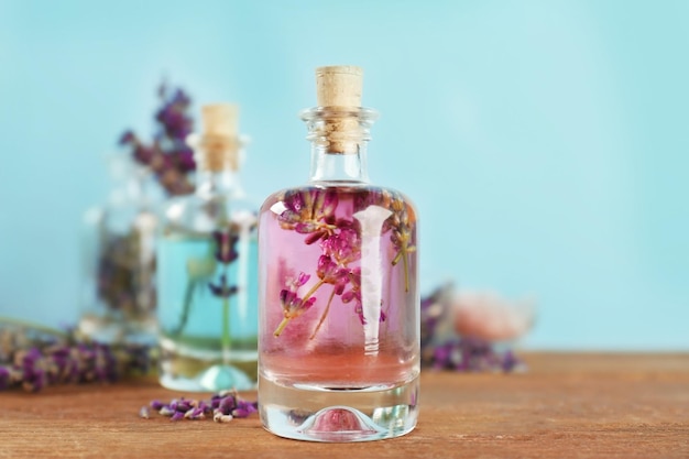 Botellas con aceite de lavanda y flores sobre fondo de pared azul