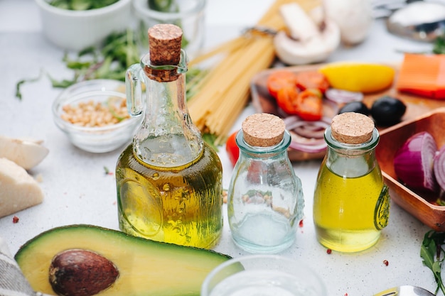 Botellas de aceite, mitad de aguacate y otros ingredientes de cocina sobre la mesa