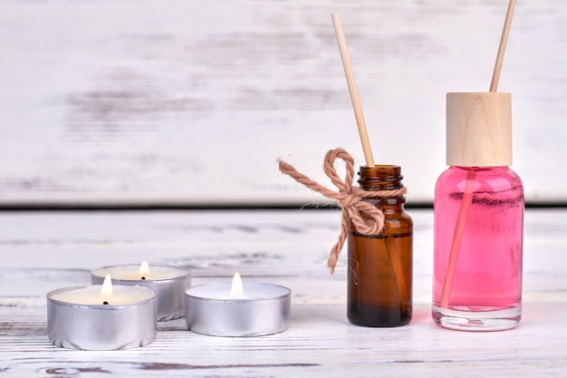 Botellas con aceite y velas encendidas sobre fondo blanco.