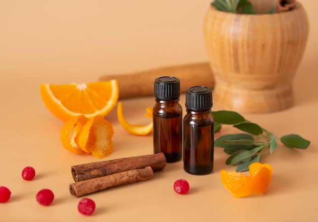 Botellas con aceites esenciales e ingredientes salvia canela naranja sobre un fondo beige