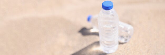 Botellas de agua de plástico de pie sobre arena caliente closeup
