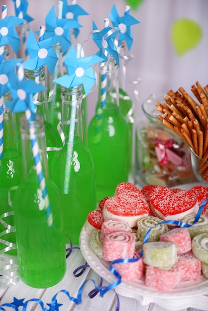 Botellas de bebida con paja y dulces sobre fondo decorativo