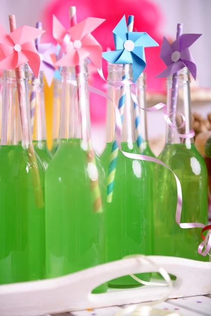 Foto botellas de bebida con paja en la mesa sobre un fondo decorativo