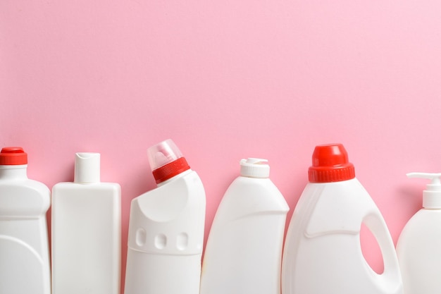 Las botellas blancas de plástico yacen sobre un fondo rosa claro Disposición de botellas con productos químicos domésticos para la limpieza y desinfección de la habitación