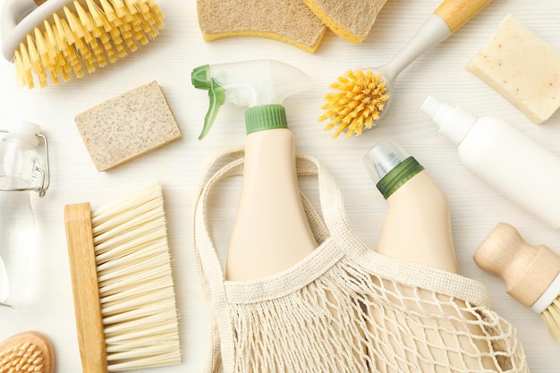 Botellas de bolsa ecológica con detergentes y herramientas de limpieza en un fondo claro vista de arriba