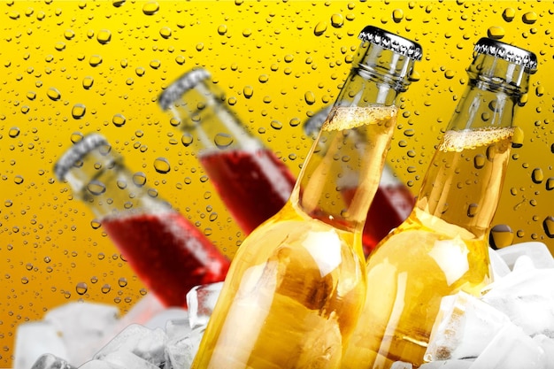 Botellas de cerveza en hielo sobre fondo de vidrio mojado