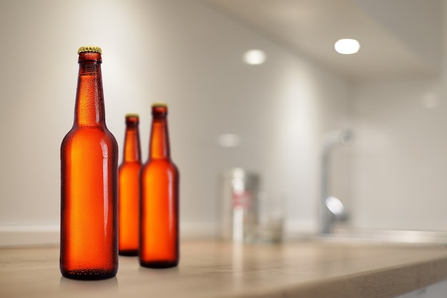 Botellas de cerveza marrón en la maqueta de la mesa de la cocina. Sin etiqueta, gotas de agua.