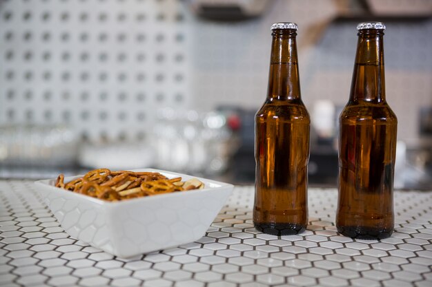 Botellas de cerveza y tazón de aperitivos en barra de bar