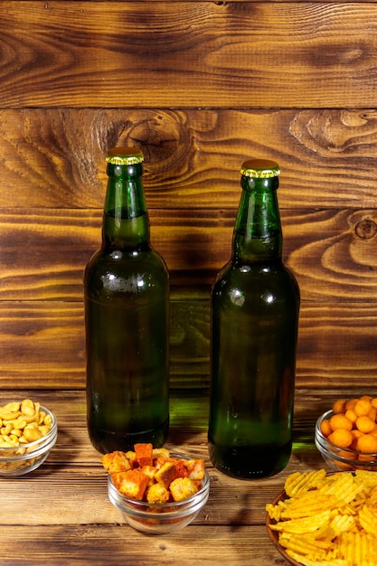 Botellas de cerveza y varios bocadillos para cerveza en la mesa de madera