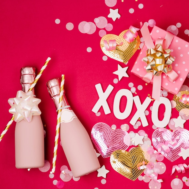 Botellas de champán con confeti y oropel sobre fondo rojo. Tema de concepto de fiesta de cumpleaños o día de San Valentín. Endecha plana, vista superior