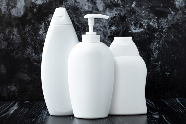 Botellas de champú de plástico blanco, jabón líquido antibacteriano y gel de ducha sobre fondo de mármol negro en el baño. Concepto de higiene, desinfección. Protección del virus de la gripe, influenza.