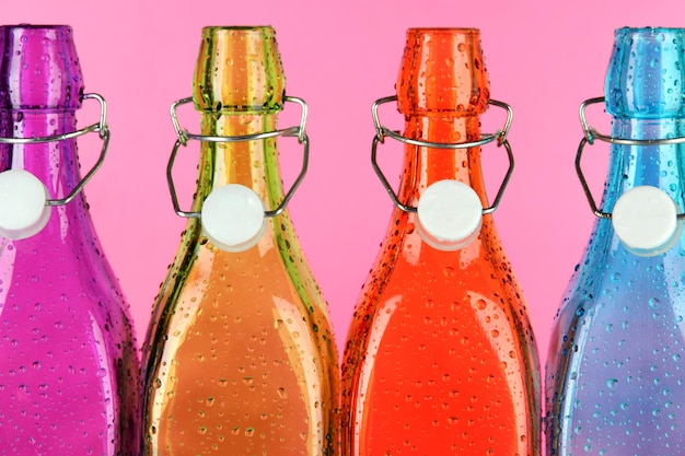 Foto botellas de colores sobre fondo rosa