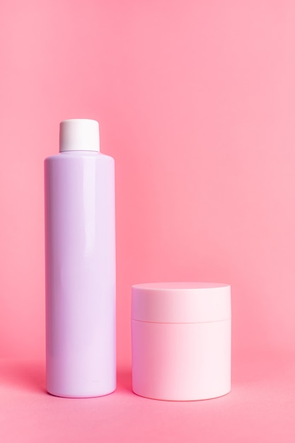 Botellas de cosméticos de color rosa y violeta claro sobre un fondo rosa