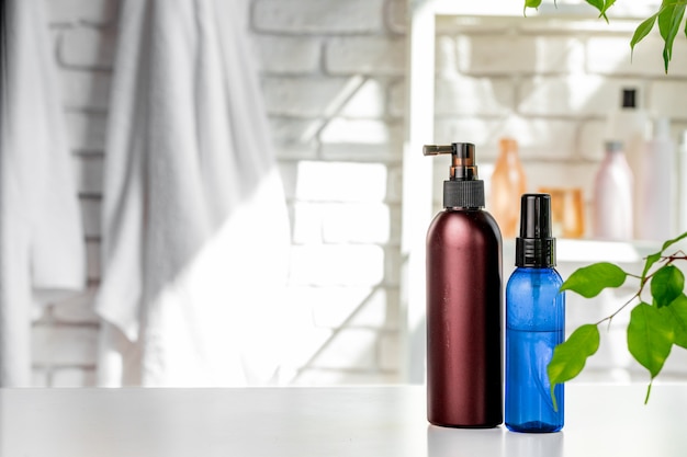 Botellas de cosméticos contra el fondo blanco de la pared del baño