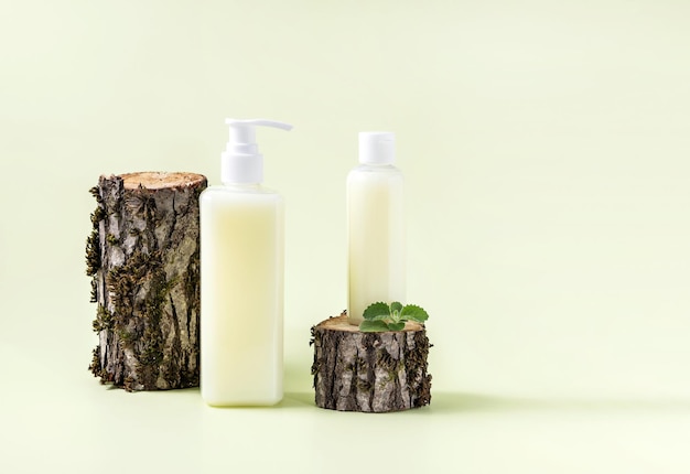 Botellas para cosméticos y corteza de árbol con musgo sobre un fondo verde claro
