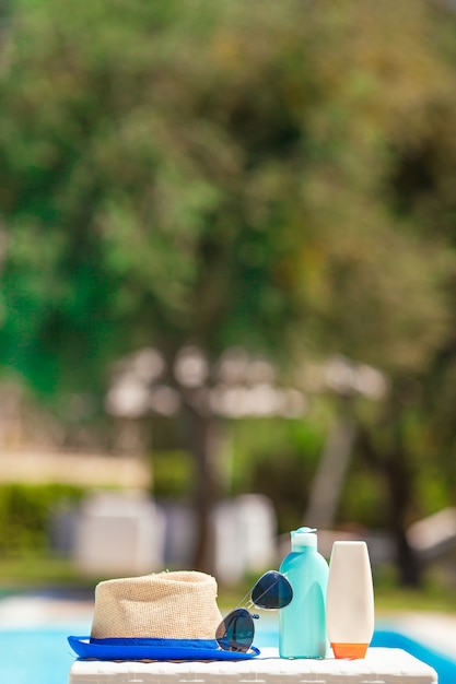 Foto botellas de crema solar, gafas, estrellas de mar en el borde de la piscina.