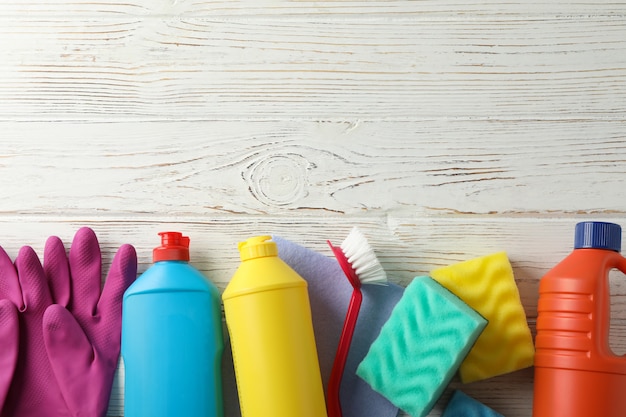 Botellas con detergente y productos de limpieza en madera, espacio para texto