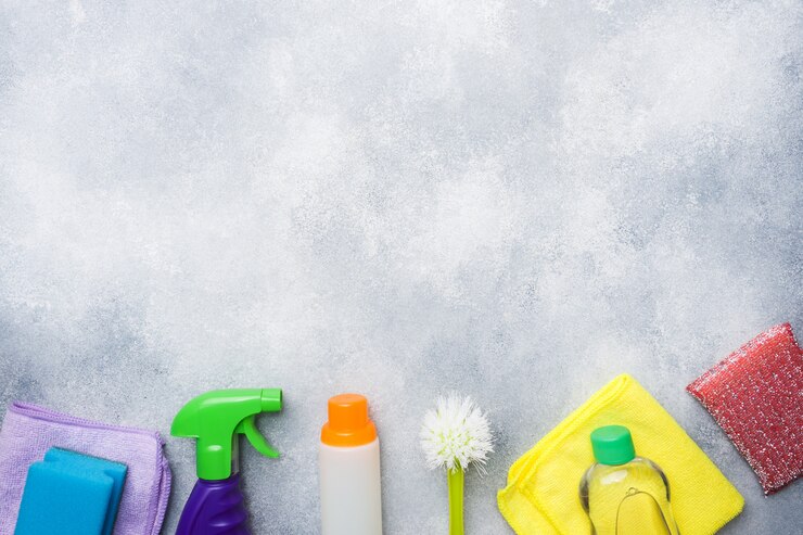 Botellas con detergentes, cepillos y esponjas sobre fondo de hormigón.