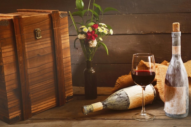 Botellas envejecidas con copa de vino en mesa de madera