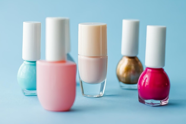 Botellas de esmalte de uñas de colores sobre fondo azul maquillaje orgánico y productos cosméticos para la marca de belleza