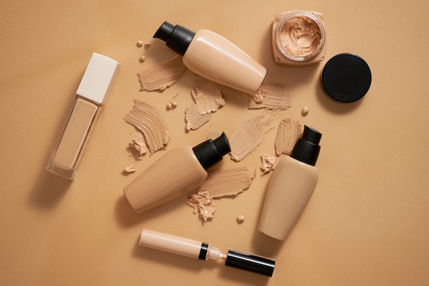 Botellas de fundamento de maquillaje y muestras en fondo beige Vista superior plana
