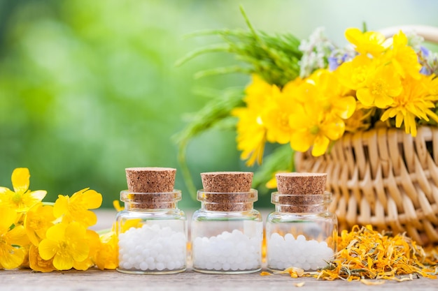 Botellas de glóbulos de homeopatía y hierbas saludables en cesta de mimbre