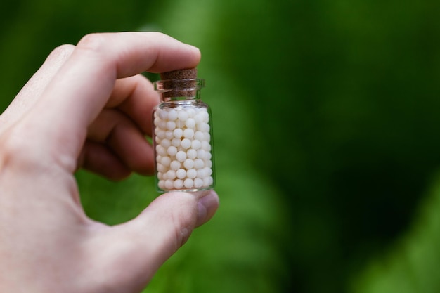 Botellas de glóbulos homeopáticos sobre fondo de helecho verde. Medicina homeopática.