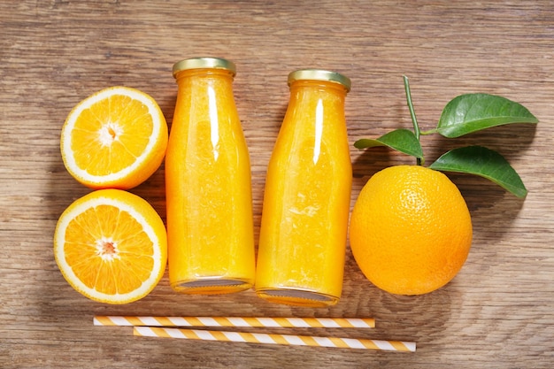 botellas de jugo de naranja con frutas frescas en un fondo de madera vista superior