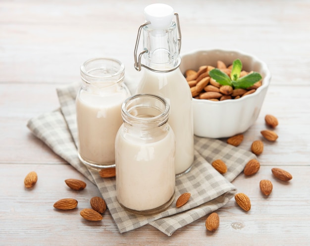 Botellas con leche de almendras y almendras en la mesa