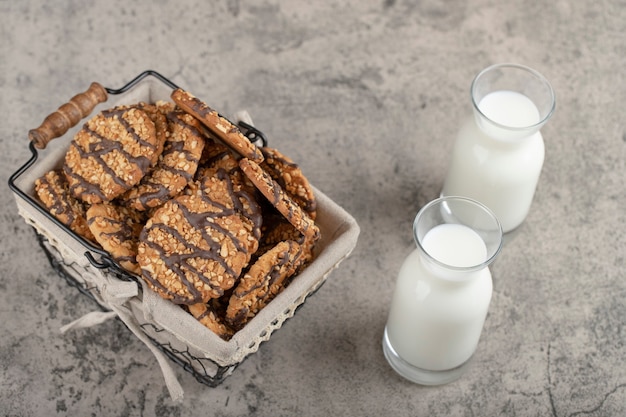 Botellas de leche con galletas en canasta colocada sobre una mesa de piedra.