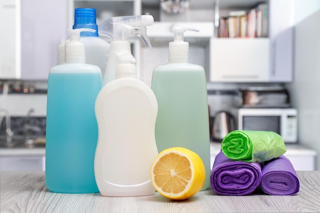 Botellas de limón líquido para lavar platos y bolsas de basura sobre fondo gris