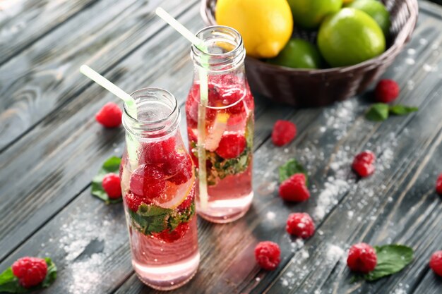 Botellas de limonada de frambuesa fresca sobre mesa de madera