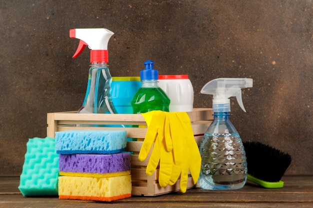 Botellas con limpiadores y detergentes en una caja sobre un fondo marrón. limpieza. productos de limpieza.