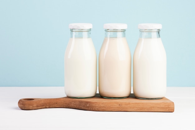 Botellas llenas de leche en tabla de cortar