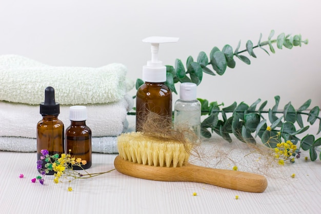 Botellas de medicamentos cepillo para el cabello y toalla en la mesa de madera blanca Problema de pérdida de cabello