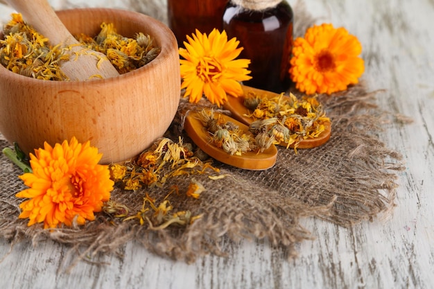 Botellas de medicina y flores de caléndula sobre fondo de madera