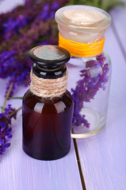 Botellas de medicina y flores de salvia sobre fondo de madera púrpura