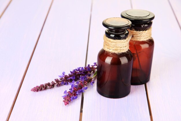 Botellas de medicina y flores de salvia sobre fondo de madera púrpura